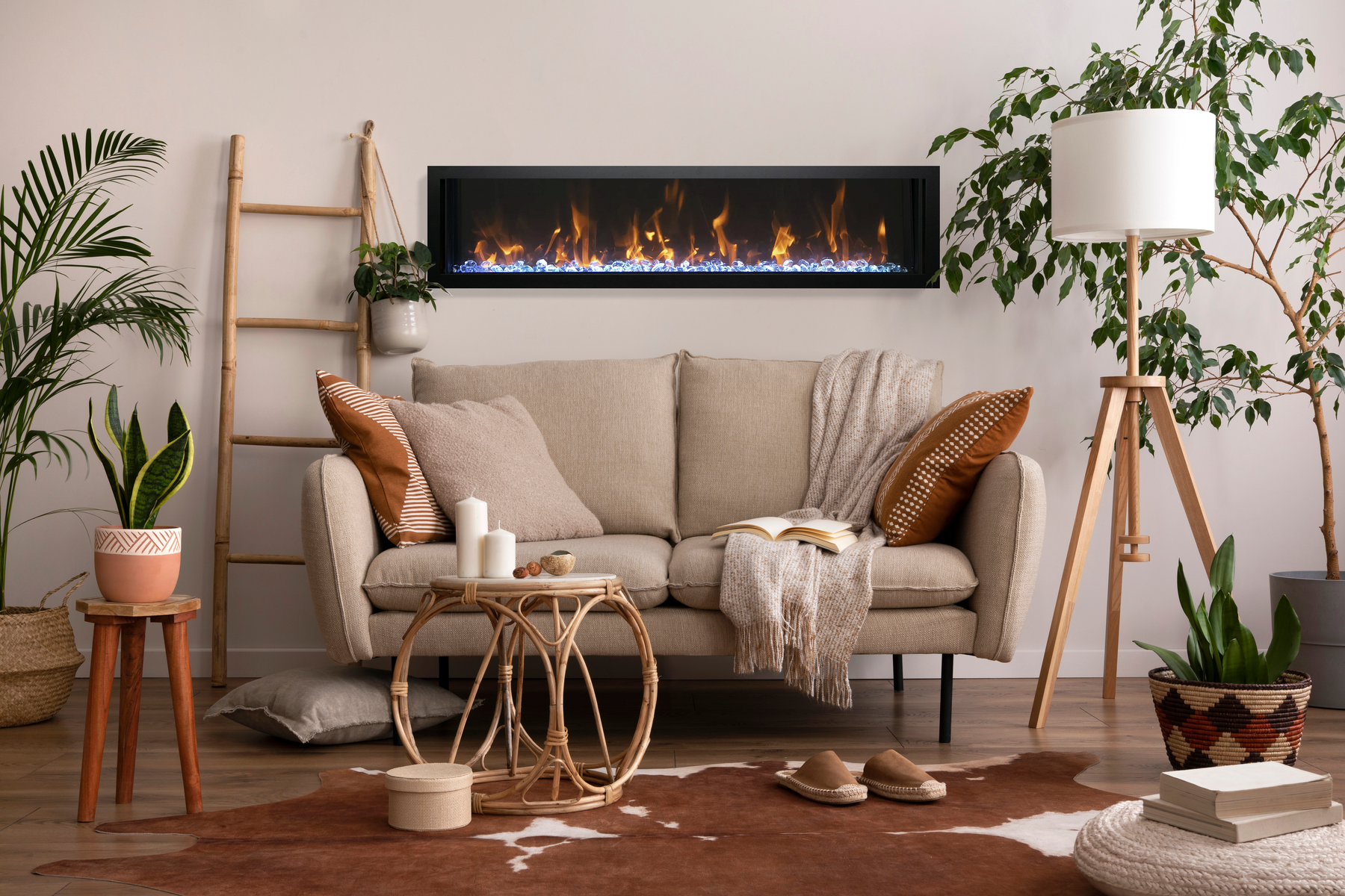 Amantii linear built-in electric fireplace installed flush in a warm boho living room wall, above a beige sofa with plants and rattan decor