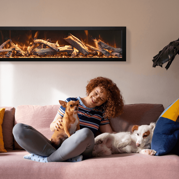 Remii DEEP electric fireplace installed in a living room with a woman and two dogs on the sofa
